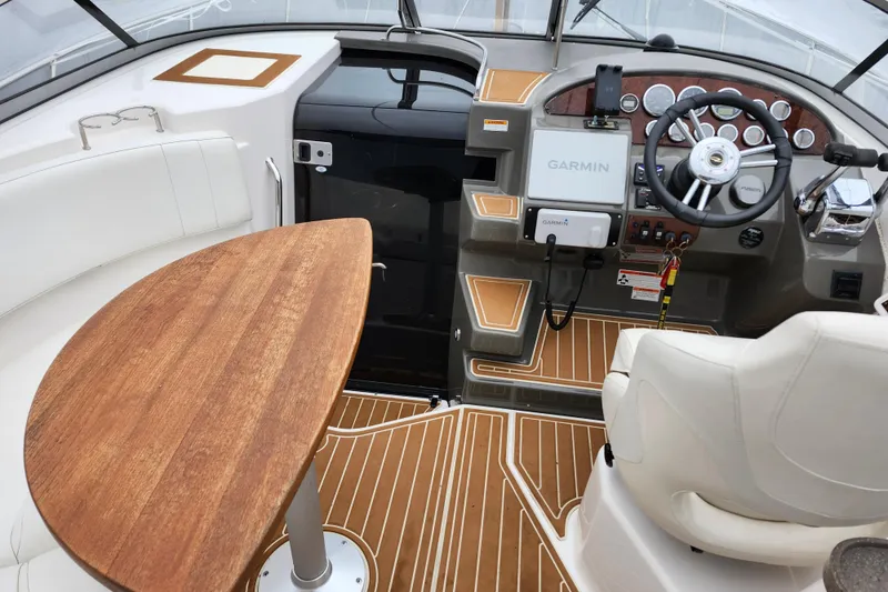 Slide: The Image of 2011 Regal 3060 Express Cruiser cockpit with steering wheel, Garmin navigation, and wooden table. - 3