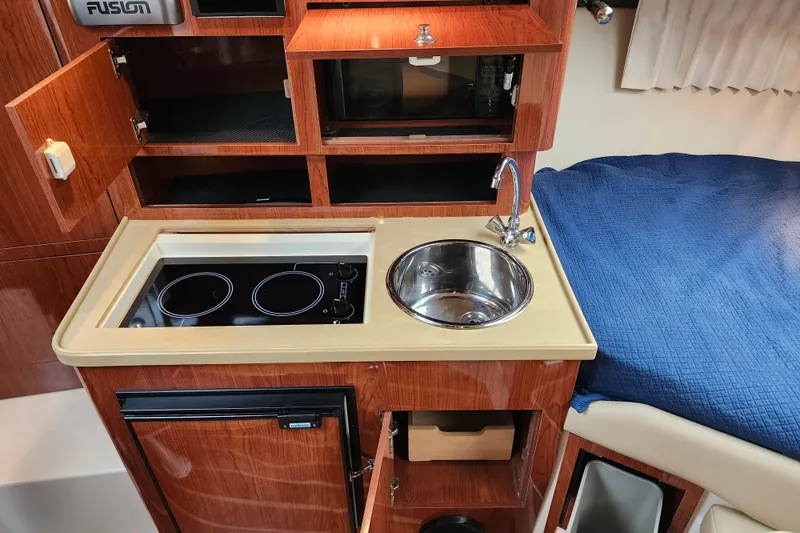 Slide: The Image of 2011 Regal 3060 Express Cruiser interior with sink, wooden cabinetry, and compact design. - 30
