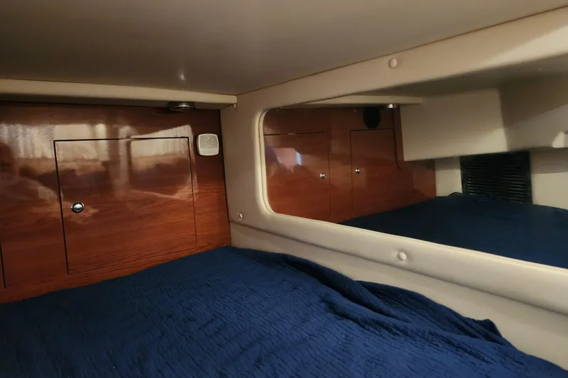 Slide: The Image of 2011 Regal 3060 Express Cruiser cabin interior with wood paneling and blue bedding. - 44