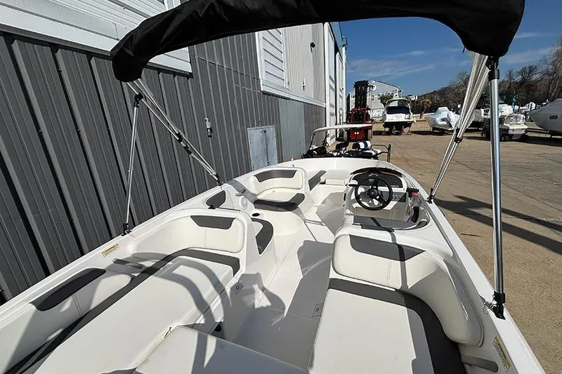 Slide: The Image of 2026 Bayliner Element E18 boat interior with seating and steering wheel, docked outdoors. - 11