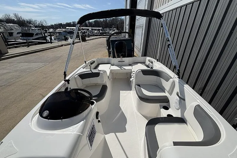 Slide: The Image of 2026 Bayliner Element E18 boat with spacious seating, docked near other boats. - 18