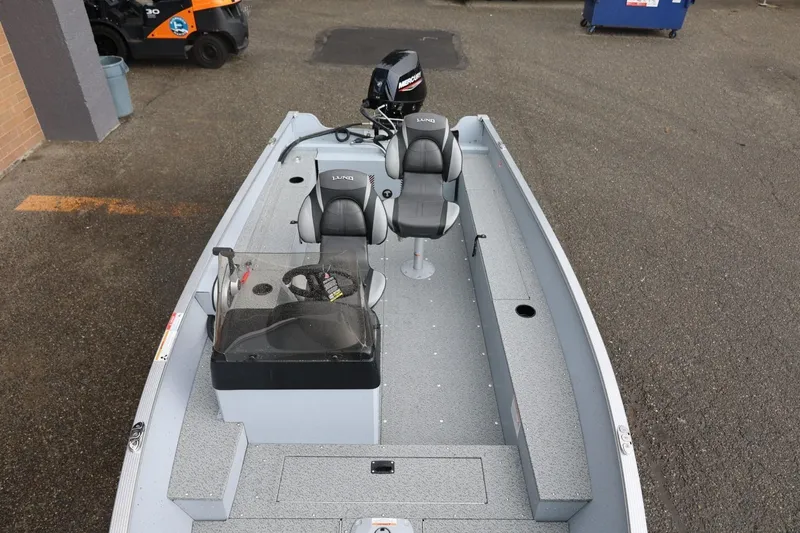 Slide: The Image of 2026 Lund 1600 Fury SS fishing boat with dual seats and motor, parked on pavement. - 30