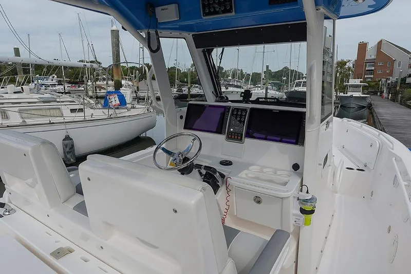 Slide: The Image of 2015 Everglades 295 Center Console boat interior at marina, featuring helm and seating. - 11