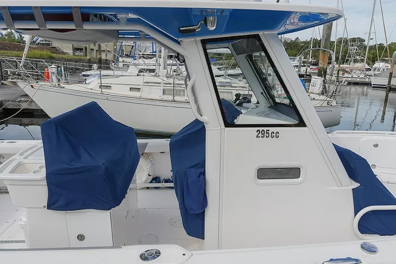 Slide: The Image of 2015 Everglades 295 Center Console boat docked at marina, featuring blue seat covers. - 35