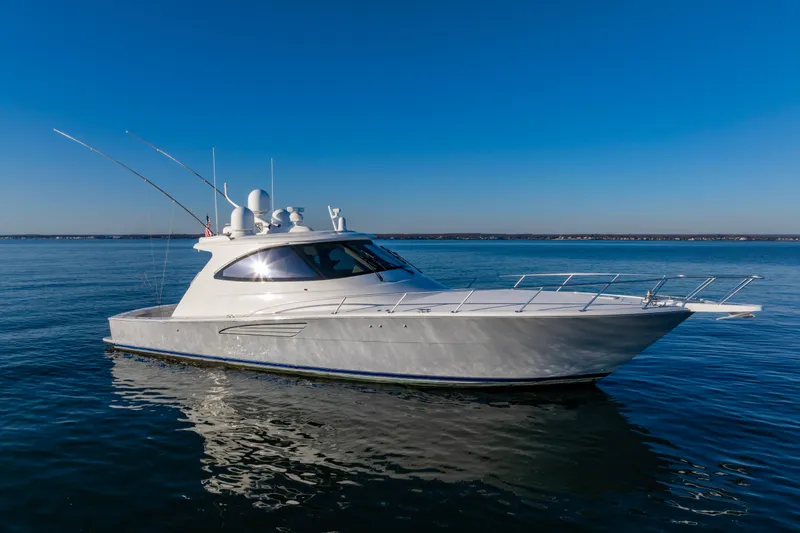 The Image of 2022 Viking 54 Sport Coupe yacht on calm blue water under clear sky. - 0