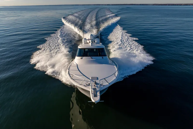 Slide: The Image of 2022 Viking 54 Sport Coupe cruising on open water, creating dynamic wake patterns. - 10