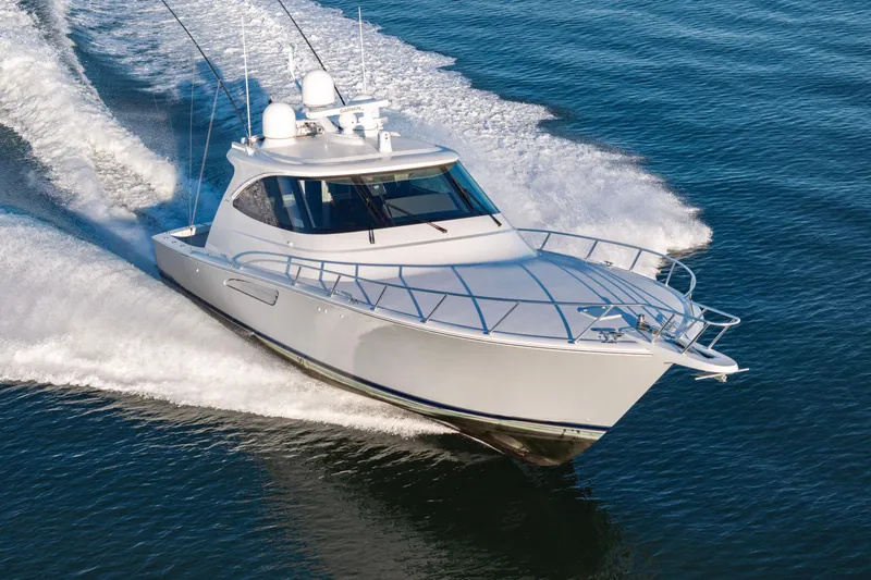 Slide: The Image of 2022 Viking 54 Sport Coupe cruising on open water, creating a dynamic wake. - 12
