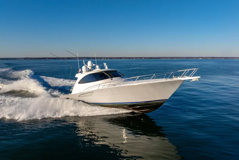 Slide: The Image of 2022 Viking 54 Sport Coupe cruising on open water under clear blue sky. - 13