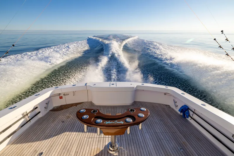Slide: The Image of 2022 Viking 54 Sport Coupe cruising, leaving a wake on calm ocean waters. - 17