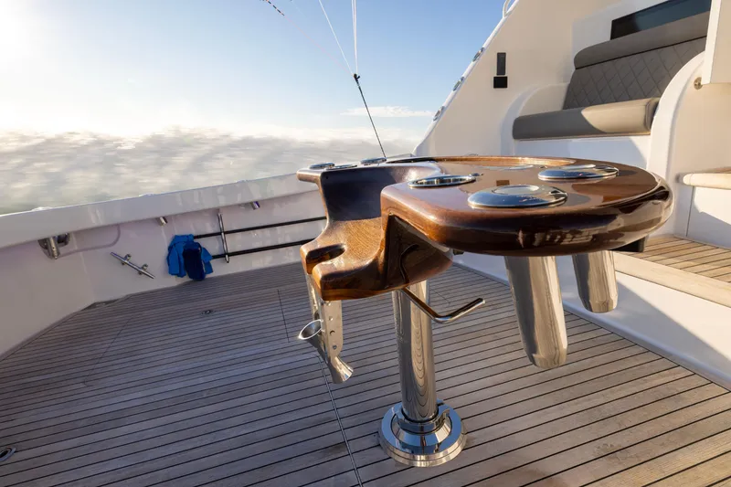 Slide: The Image of 2022 Viking 54 Sport Coupe yacht deck with polished wood table and seating. - 19