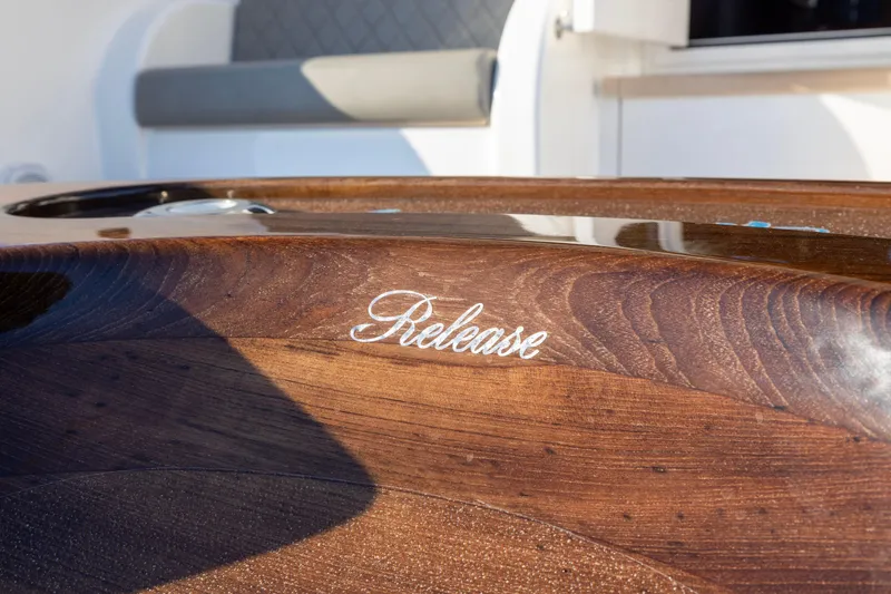 Slide: The Image of Polished wood detail on 2022 Viking 54 Sport Coupe yacht, featuring "Release" inscription. - 21