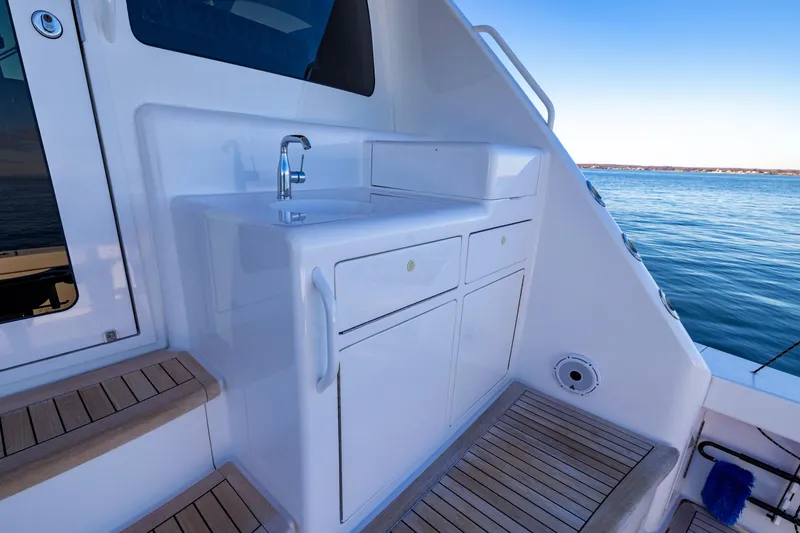 Slide: The Image of 2022 Viking 54 Sport Coupe yacht with outdoor sink and ocean view. - 24