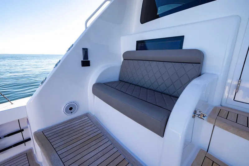 Slide: The Image of 2022 Viking 54 Sport Coupe boat with cushioned seating and wooden deck, overlooking the ocean. - 25