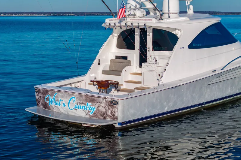 Slide: The Image of 2022 Viking 54 Sport Coupe yacht on calm blue water, rear view. - 5