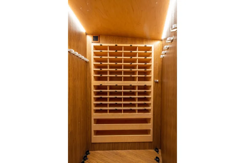 Slide: The Image of Wooden storage cabinet inside 2022 Viking 54 Sport Coupe yacht, featuring multiple shelves and hooks. - 54