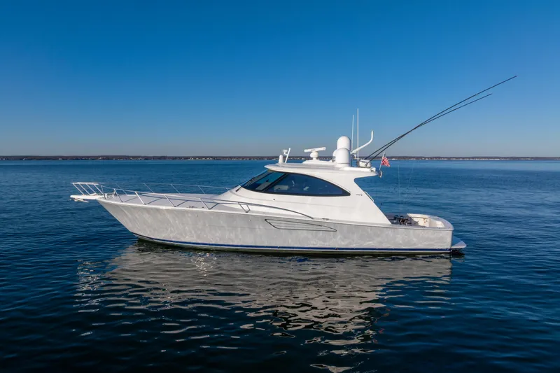 Slide: The Image of 2022 Viking 54 Sport Coupe yacht on calm blue water under clear sky. - 6