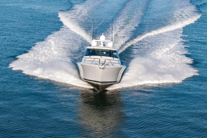 Slide: The Image of 2022 Viking 54 Sport Coupe cruising on open water, creating a dynamic wake. - 9