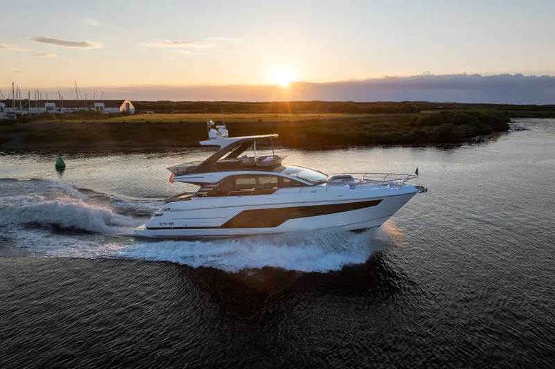 The Image of 2026 Fairline Squadron 58 yacht cruising at sunset on a serene waterway. - 0