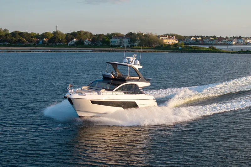 Slide: The Image of 2026 Fairline Squadron 58 yacht cruising on a serene waterway at sunset. - 5