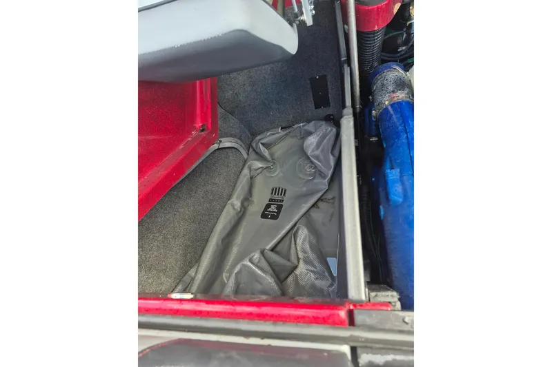 Slide: The Image of 2022 MasterCraft X24 interior storage compartment with gray bag and blue tubing. - 29