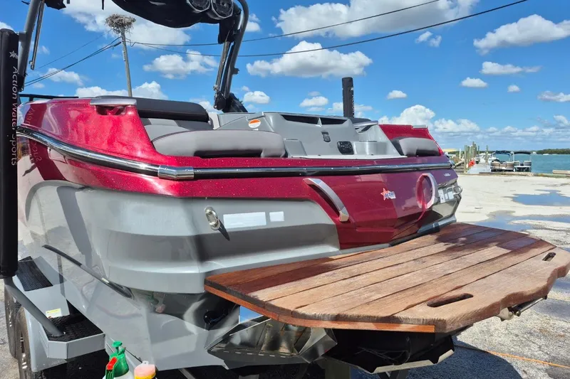Slide: The Image of 2022 MasterCraft X24 boat with red and gray finish, docked by the water. - 7