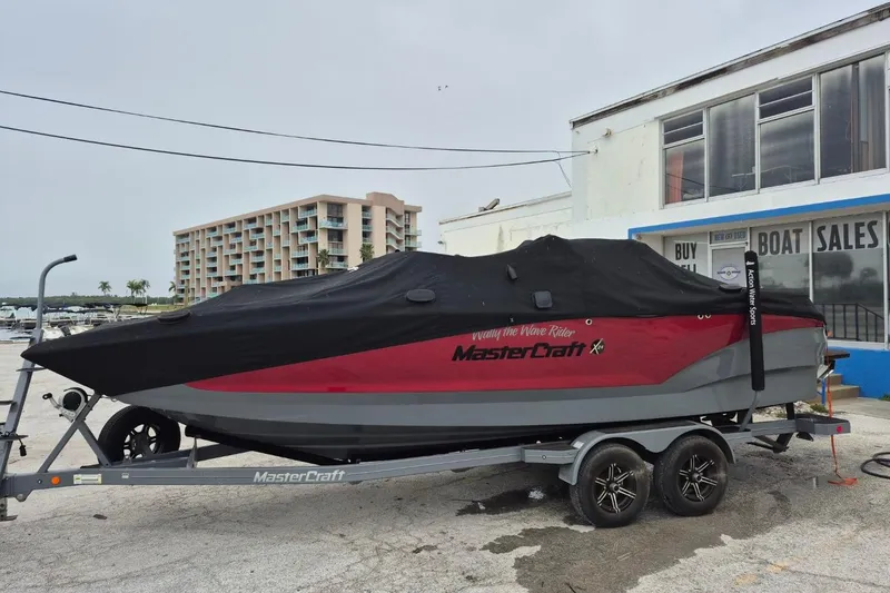 Slide: The Image of 2022 MasterCraft X24 boat covered on trailer near boat sales building. - 8
