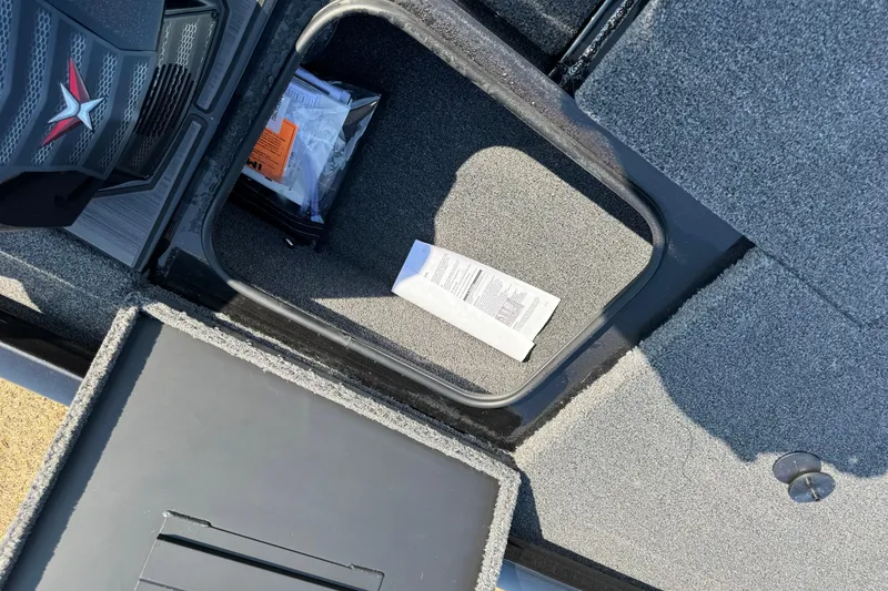 Slide: The Image of Open storage compartment in 2026 Vexus Defender 181 boat, showing documents and carpeted interior. - 15