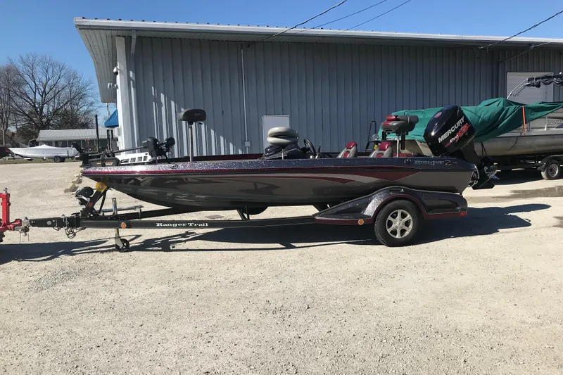 Slide: The Image of 2016 Ranger Z118 Comanche boat on trailer, parked outdoors near a metal building. - 12