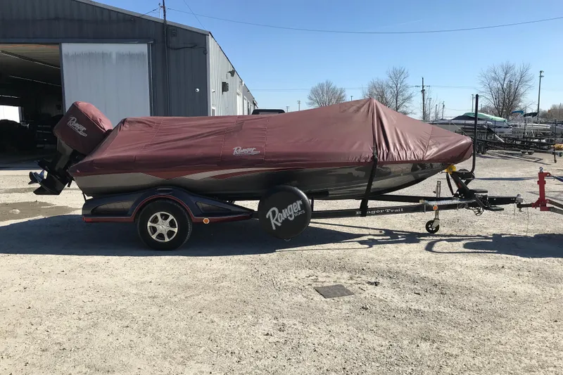 Slide: The Image of 2016 Ranger Z118 Comanche boat with maroon cover on trailer, parked outdoors. - 27