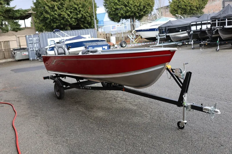 Slide: The Image of 2026 Lund 1600 Fury Tiller boat on trailer, red and silver, parked outdoors. - 10