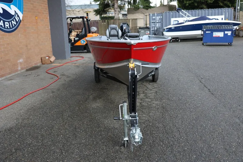 Slide: The Image of 2026 Lund 1600 Fury Tiller boat on trailer, parked outdoors near marine shop. - 12