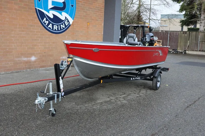 Slide: The Image of 2026 Lund 1600 Fury Tiller boat in red on a trailer outside a marine shop. - 14