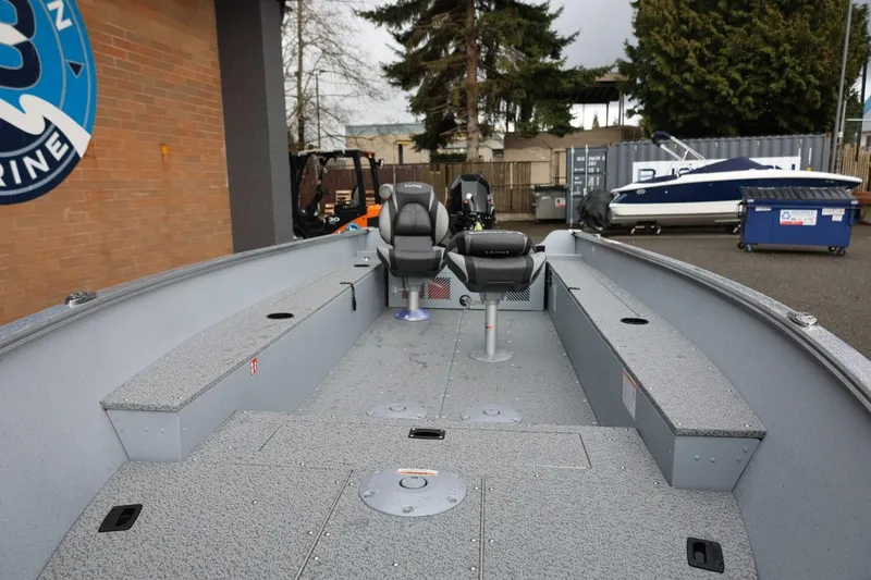 Slide: The Image of 2026 Lund 1600 Fury Tiller boat interior with seating, parked outdoors. - 17