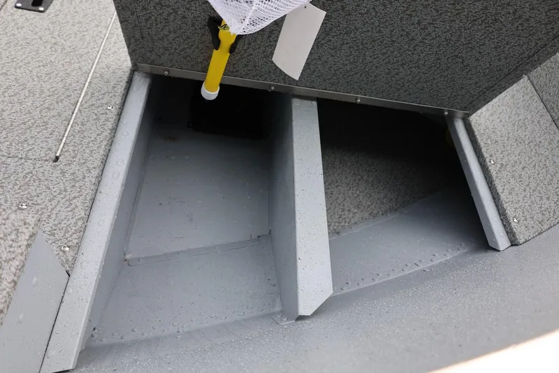 Slide: The Image of 2026 Lund 1600 Fury Tiller boat interior, featuring storage compartment and textured flooring. - 19