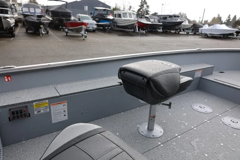 Slide: The Image of 2026 Lund 1600 Fury Tiller boat interior with seating, parked among other boats. - 22