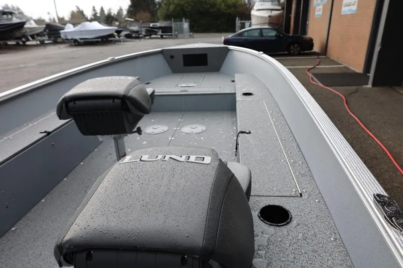 Slide: The Image of 2026 Lund 1600 Fury Tiller boat interior with wet seats, parked near a garage. - 23