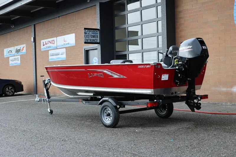Slide: The Image of 2026 Lund 1600 Fury Tiller boat in red, parked on a trailer outside a dealership. - 4