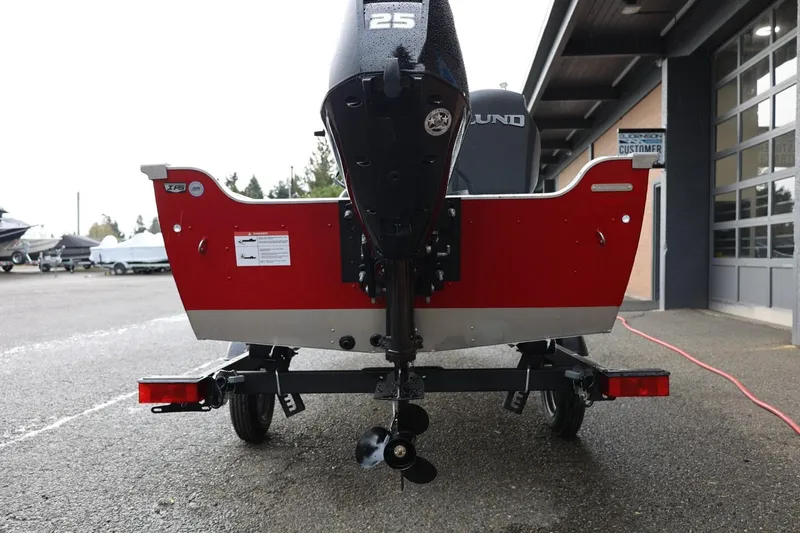 Slide: The Image of 2026 Lund 1600 Fury Tiller boat, red exterior, parked on a trailer outside a building. - 6