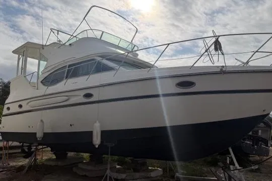 Slide: The Image of 2000 Maxum 4100 SCA yacht on dry dock under a cloudy sky. - 13