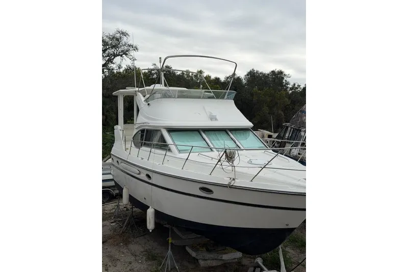 Slide: The Image of 2000 Maxum 4100 SCA yacht on land, white exterior, overcast sky. - 3