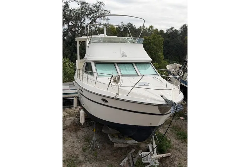 Slide: The Image of 2000 Maxum 4100 SCA yacht on land, surrounded by trees, overcast sky. - 5
