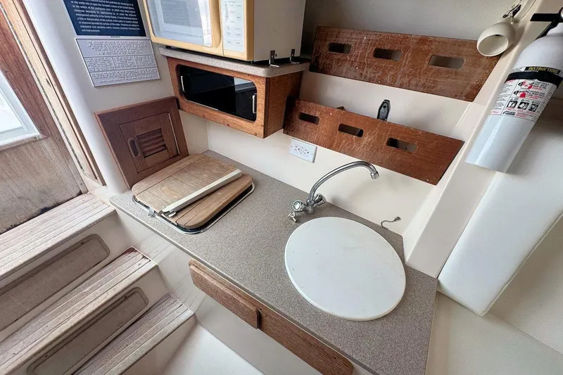 Slide: The Image of 2005 Contender 35 Express Side Console interior with sink, microwave, and fire extinguisher. - 23