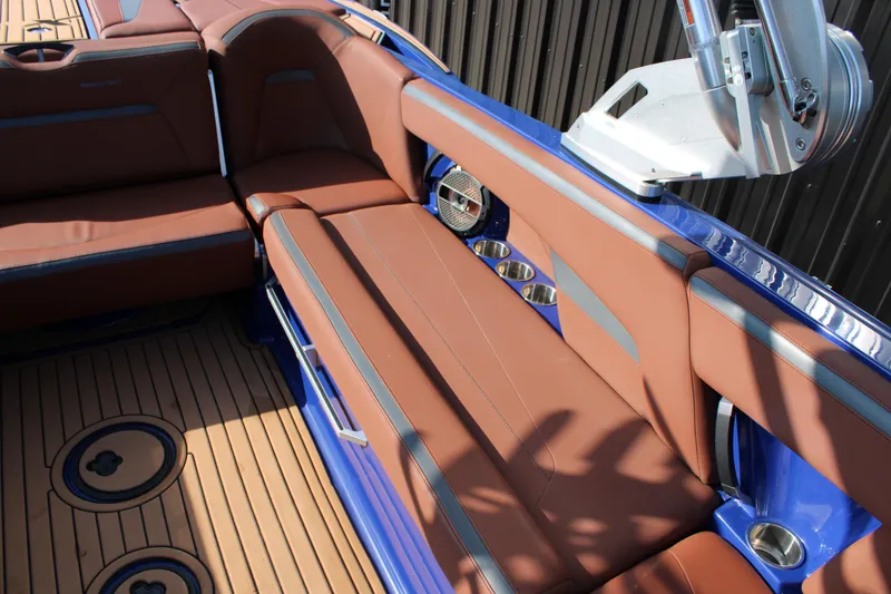 Slide: The Image of 2021 MasterCraft XStar interior with brown seating and blue accents, featuring cup holders. - 13
