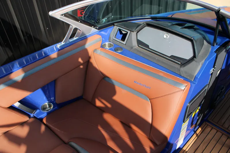 Slide: The Image of 2021 MasterCraft XStar boat interior with brown leather seats and blue accents. - 8