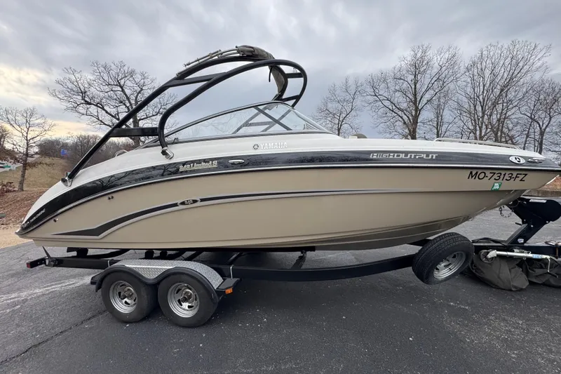 Slide: The Image of 2012 Yamaha Boats 242 Limited S on trailer, parked outdoors with overcast sky. - 2