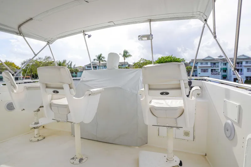 Slide: The Image of 1991 Viking 65 Cockpit boat helm with white captain chairs and covered controls. - 47