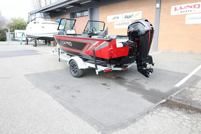 Slide: The Image of 2026 Lund 1775 Impact XS Sport boat on trailer, parked outside dealership. - 8