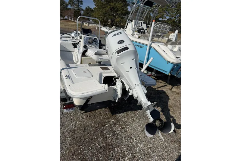 Slide: The Image of 2006 Carolina Skiff JV17 boat with outboard motor, parked on gravel. - 2