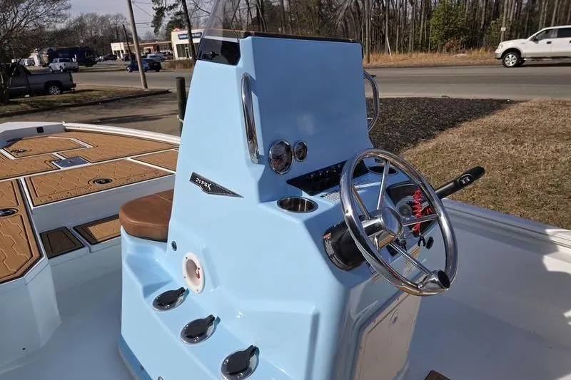 Slide: The Image of 2026 Avid 21 FSX boat console with steering wheel and controls, parked outdoors. - 9