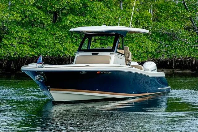 The Image of 2019 Chris-Craft Catalina 30 boat on calm water, surrounded by lush greenery. - 0